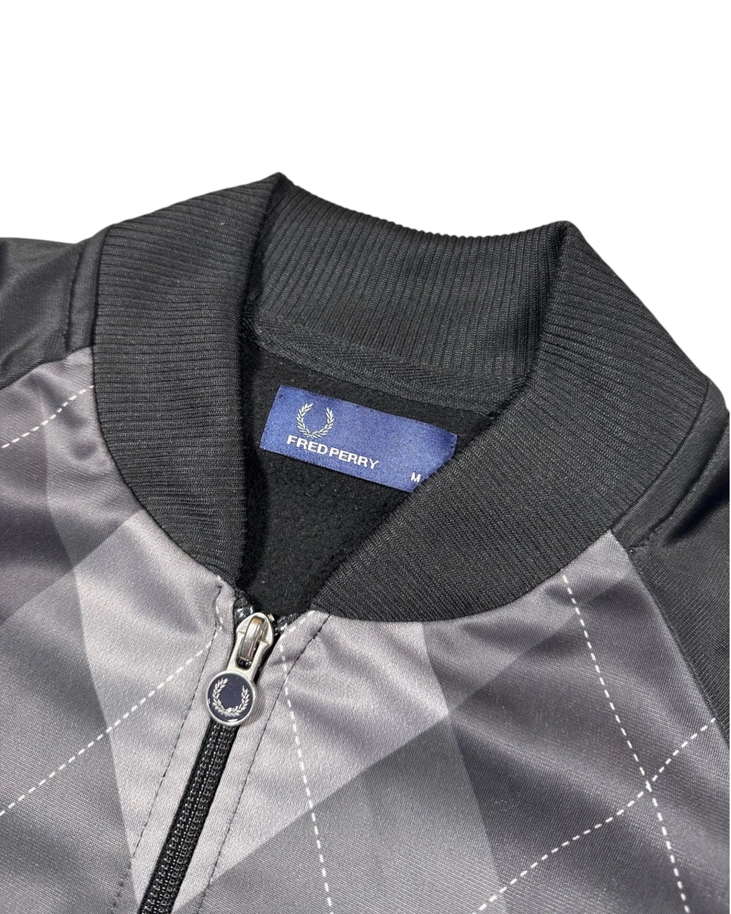 GEGENHALT: Fred Perry Trainingsjacke mit grauem und schwarzem Argyle-Muster, Polyester, durchgehendem Reißverschluss und Rippstrickbündchen.