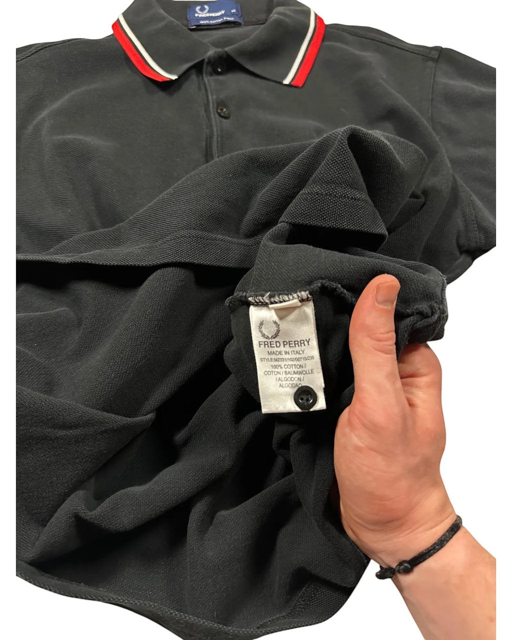GEGENHALT. Schwarzes Herren-Poloshirt aus Baumwolle mit roten und weißen Kragenstreifen und Fred Perry Logo.