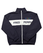 GEGENHALT. Dunkelblauer Windbreaker mit weißem Streifen und Fred Perry Schriftzug, bunte Lorbeerkränze auf der Brust.